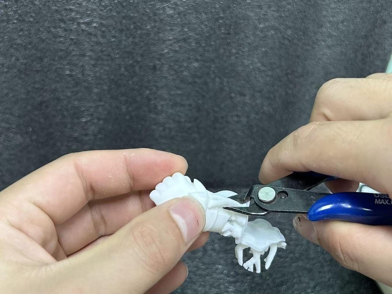 Removing resin 3D printing support tabs with precision flush cutters before assembly.