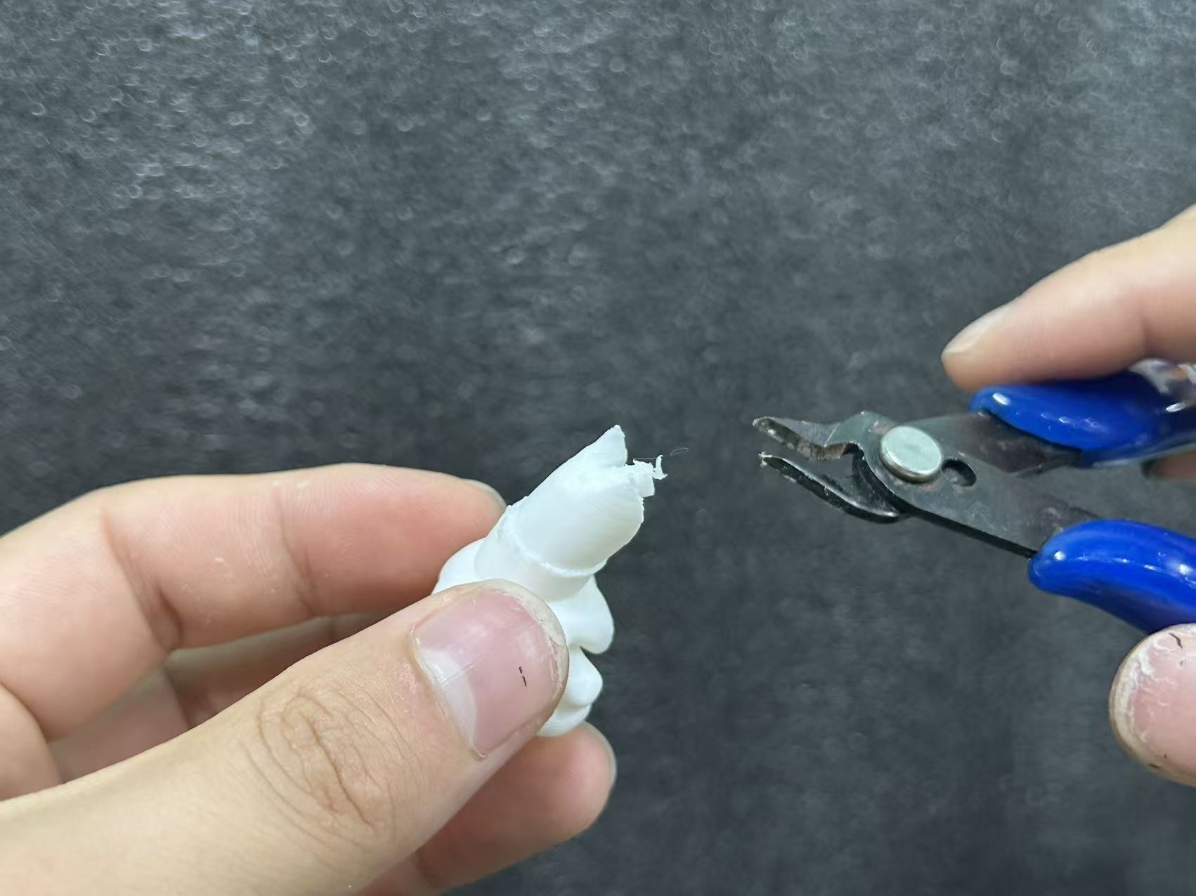 Removing the final support mark from a resin 3D printed miniature part.